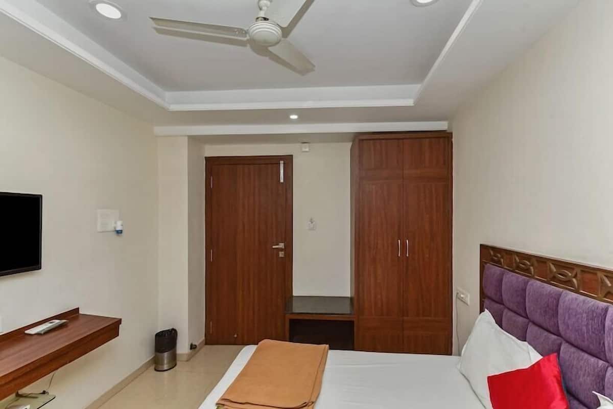 A bedroom with a bed, a TV, a wardrobe, and a ceiling fan.