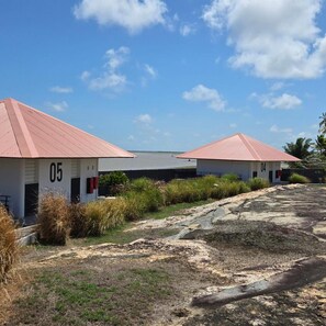Twee gelijkvloerse gebouwen met platte daken, genummerd 05 en 04, naast een verhard gebied met schaarse beplanting.