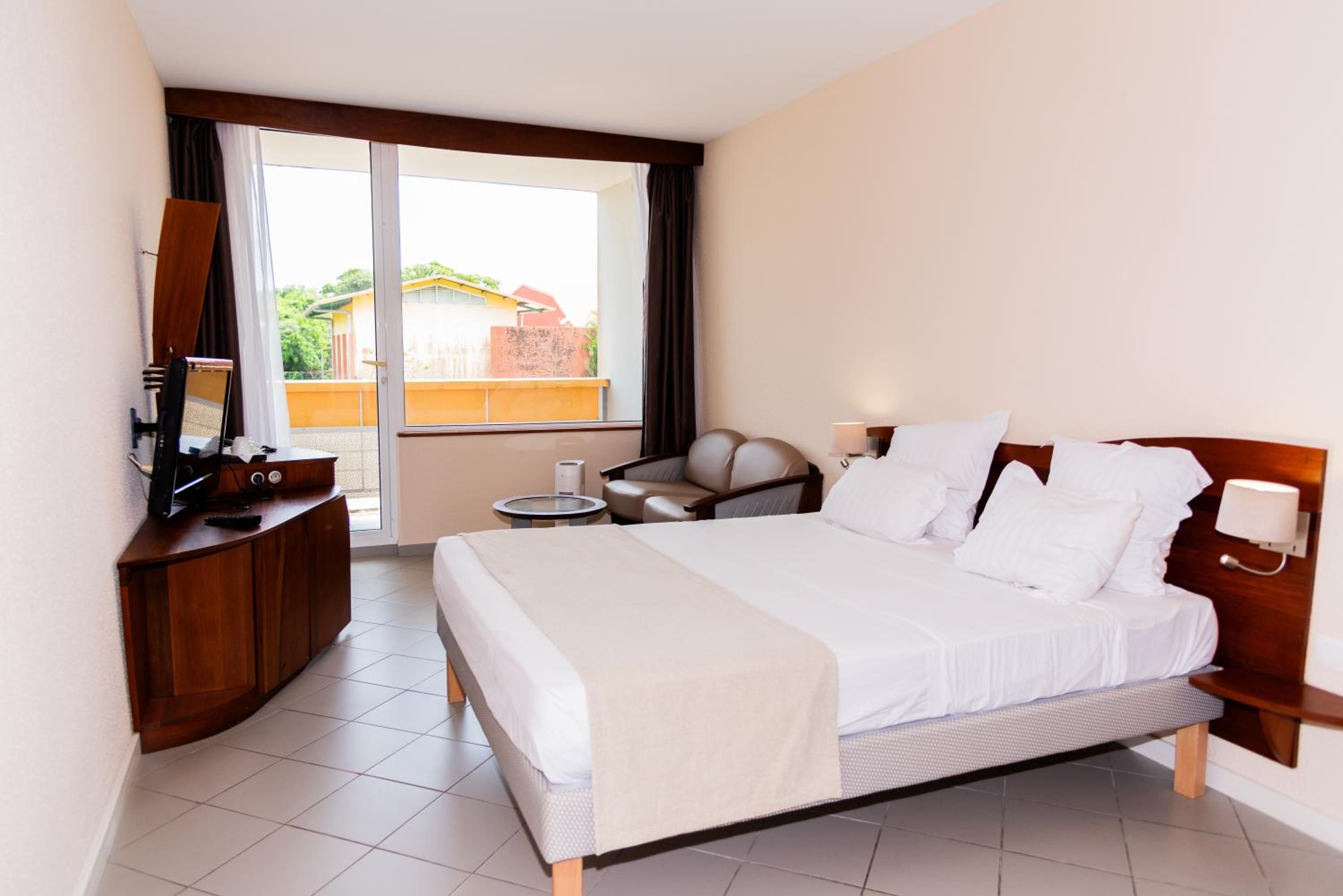 Habitación de hotel con cama, escritorio, silla y vista al exterior.