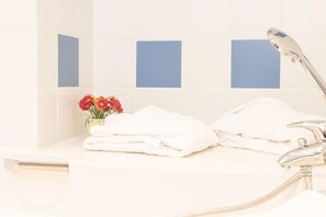 Een badkamer met witte tegels, een wastafel, een spiegel en een kraan.