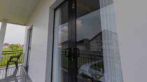 A balcony with a glass door, a chair, and a small table with fruits. - Casa Yumi (Denpasar)