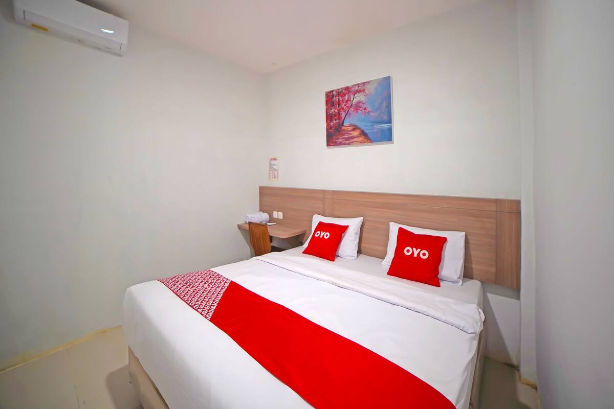 A hotel room with a bed, a desk, and a nightstand.