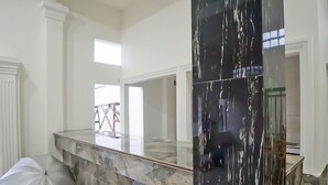 Un amplio vestíbulo de hotel con un mostrador de recepción de mármol, un espejo grande y vistas al exterior.
