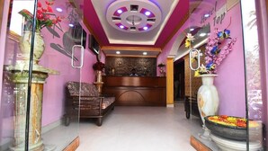 A hotel lobby with a reception desk, a sofa, and decorative vases. - Hotel Shell Top  (Panaji)