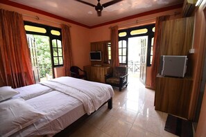 A hotel room with two beds, a TV, a desk, and a chair. - Hotel Shell Top  (Panaji)