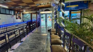 A restaurant with a checkered floor, a long counter, and a refrigerator. - Hotel Shell Top  (Panaji)