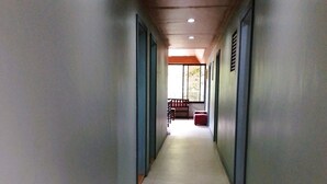 A long, narrow hallway with patterned flooring, wooden ceiling, and walls with a light color. - Felli's Guest House  (Tagbilaran)