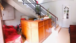 A staircase leading to a second floor, a wooden bench, a red sofa, and a cabinet with a 'WELCOME' sign. - Felli's Guest House  (Tagbilaran)
