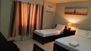A hotel room with two beds, a nightstand with a lamp, a painting of a cityscape, and a window with curtains. - Felli's Guest House  (Tagbilaran)
