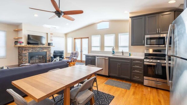 A modern kitchen with a dining area, a fireplace, and a ceiling fan. - Serene Point Loma Retreat - Modern 2BR with Views of Point Loma (San Diego)