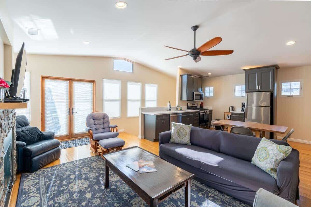 A spacious living room with a dark-colored sofa, a coffee table, and a ceiling fan.