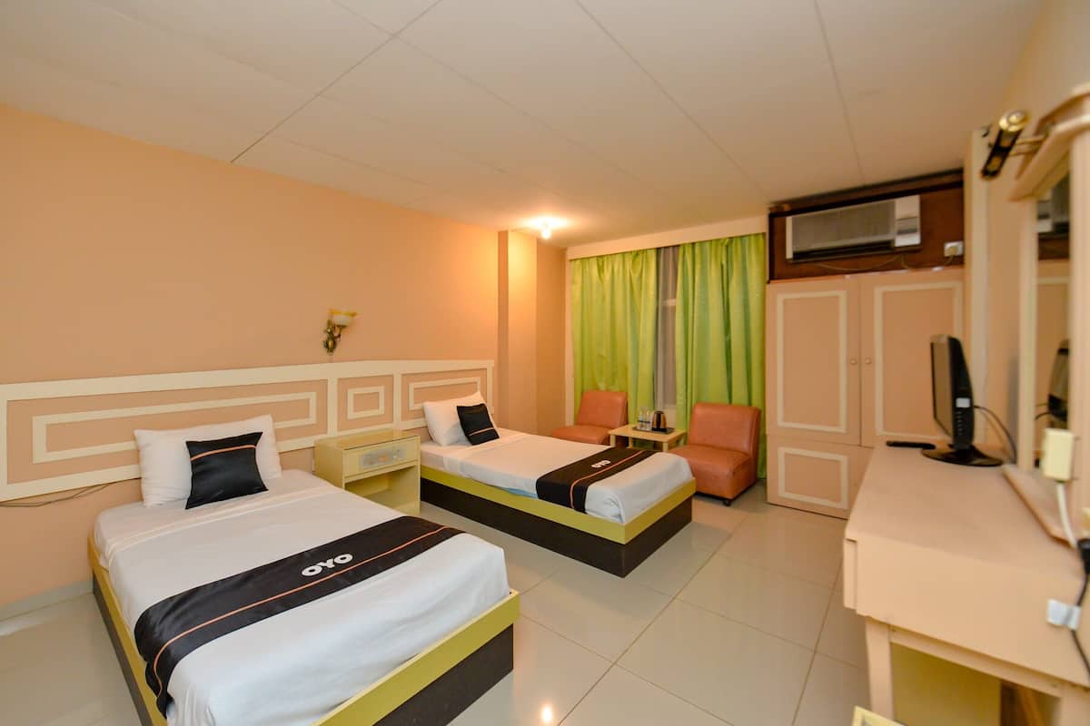 A hotel room with two beds, a desk, a TV, and a wardrobe.