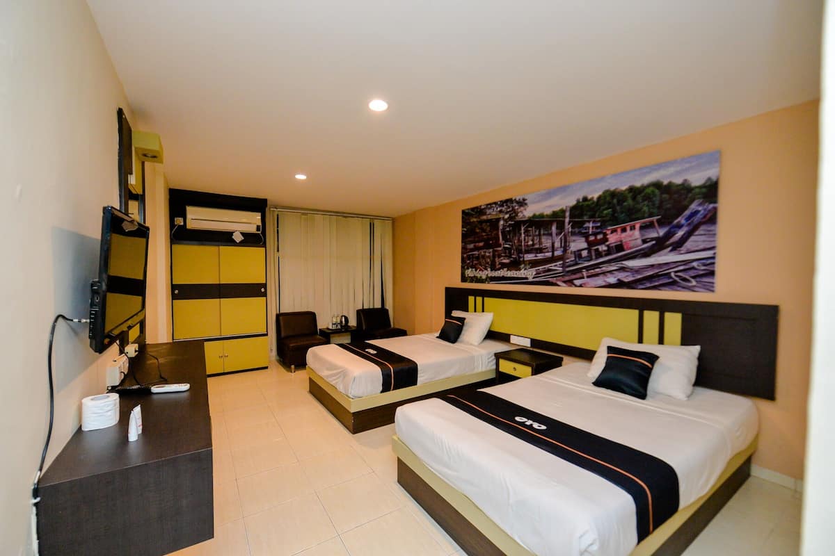 A hotel room with two beds, a desk, a TV, and a painting on the wall.