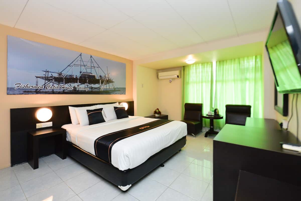 A hotel room with a large bed, a desk, a chair, a TV, and a painting on the wall.