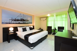 Una habitación de hotel con una cama grande, un escritorio, una silla, un televisor y un cuadro en la pared.