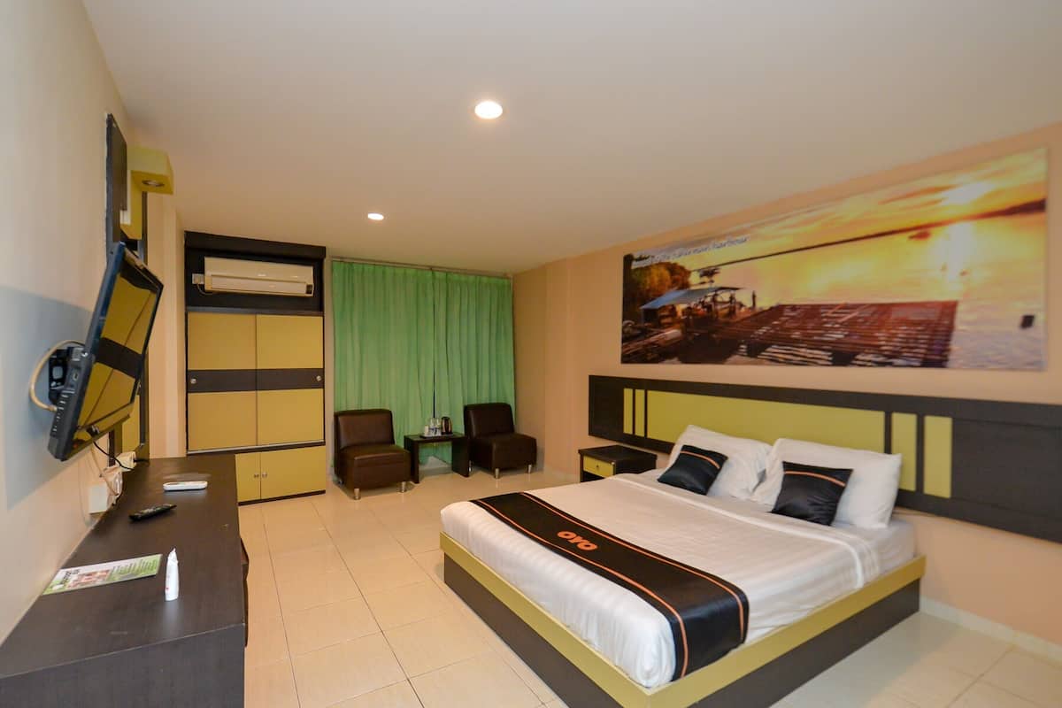 A hotel room with a bed, a desk, a TV, and a green curtain.