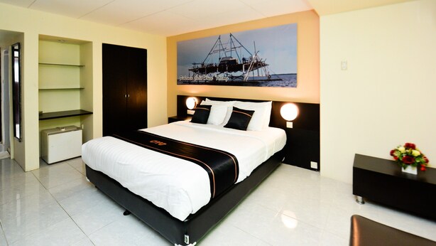 Una habitación de hotel moderna con una cama grande, una mesita de noche, un escritorio y un estante en la pared.