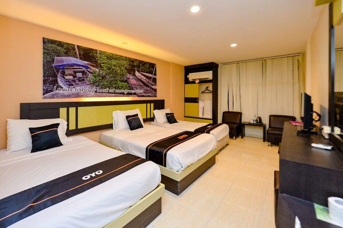A hotel room with two beds, a desk, and a large painting of a fishing boat.