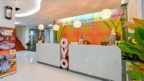 Zona de recepción de un hotel con mostrador de mármol, una mesa de recepción y una pared colorida con el letrero 'Sei Datang'.