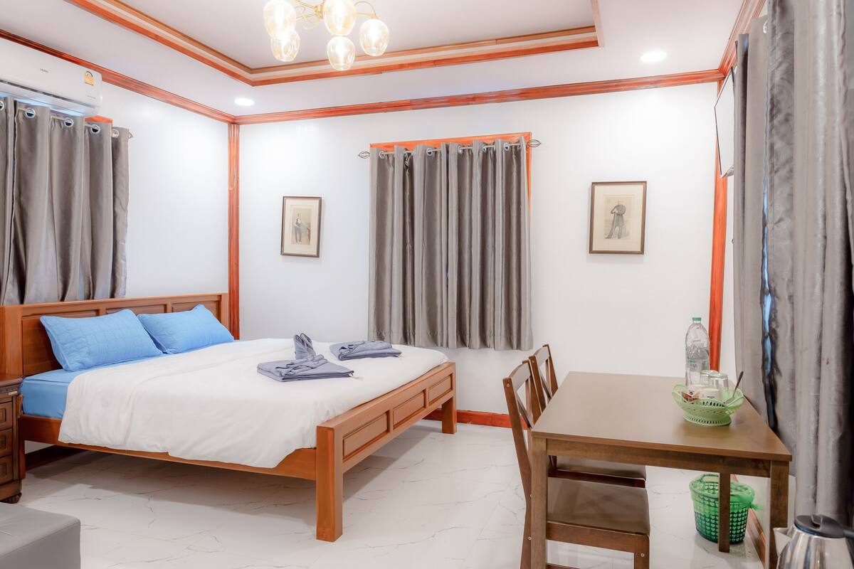 Um quarto com cama de madeira, uma mesinha e uma cadeira.