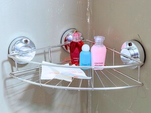 Rincón de baño con toallero cromado que sostiene una botella de gel de ducha, una botella de champú y una botella de acondicionador.