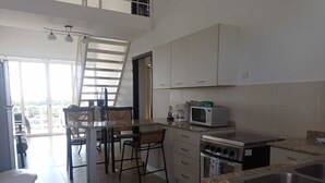 A modern kitchen with white cabinets, a microwave, an oven, and a dining area with chairs and a table. - 🌤️Gulf Sea View Condo in San Carlos 4 bdr near Coronado, El Valle&🏄‍♂️schools (San Carlos)