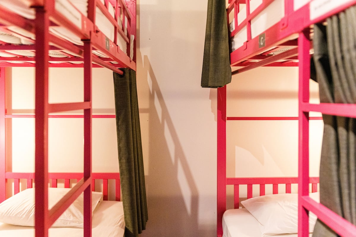 Un corredor estrecho con literas a ambos lados, cada una con colchón y almohada.