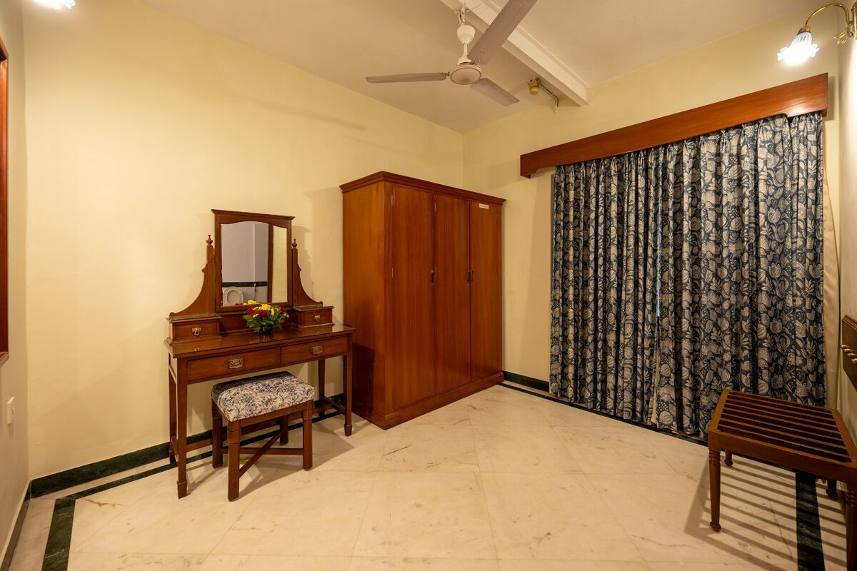 A room with a wooden desk, a mirror, a wardrobe, and a patterned curtain.