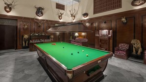 A billiards room with a pool table, wooden paneling, and mounted animal heads on the walls. - Umed Bhawan Palace (Kota)