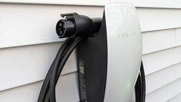 A Tesla charging station mounted on a white exterior wall.