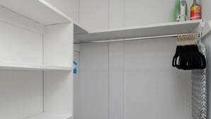 A walk-in closet with white shelves, a hanging rod, and a small shelf with cleaning supplies. - The Pratt Studio · Near Mystic, Casinos + USCGA (Groton)
