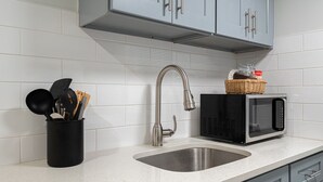 A kitchen with a stainless steel sink, a modern faucet, and a black microwave on the countertop.