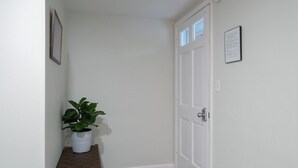A hallway with a white door, a small bench, and a potted plant.