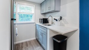 A compact kitchen with a microwave, sink, and cabinets.