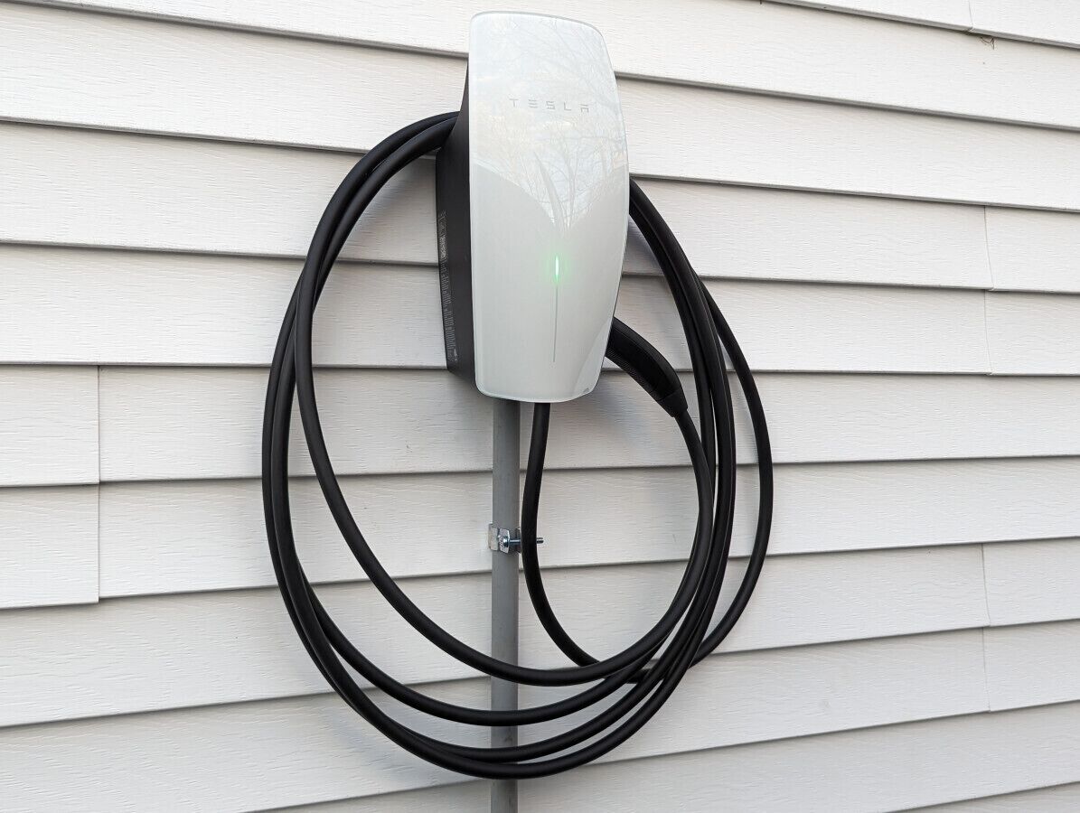 A Tesla charging station mounted on a white exterior wall.