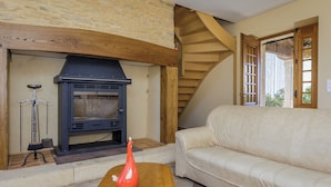 A cozy living room with a stone fireplace, a sofa, and a wooden coffee table.
