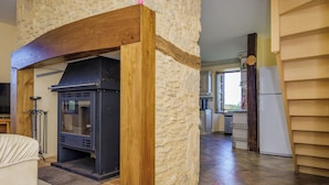 A kitchen with a stone wall, a wood-framed arch, a black stove, and a white refrigerator.