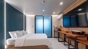 A modern hotel room with a bed, a desk, a flat-screen TV, and a sliding door. - The on tourist hotel (Seosan)