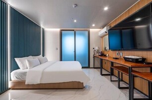 Una habitación de hotel moderna con una cama, un escritorio, un televisor de pantalla plana y una puerta corredera.