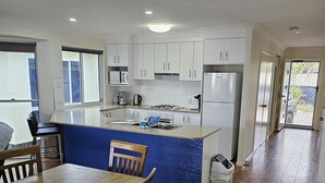 Una cocina moderna con armarios blancos, encimera azul y suelo de madera.