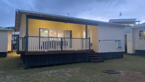 Una casa móvil de un piso con terraza cercada y un pequeño porche.