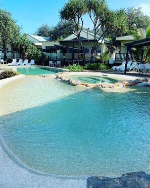 Une piscine aux eaux cristallines, avec des chaises longues et un bâtiment en arrière-plan.