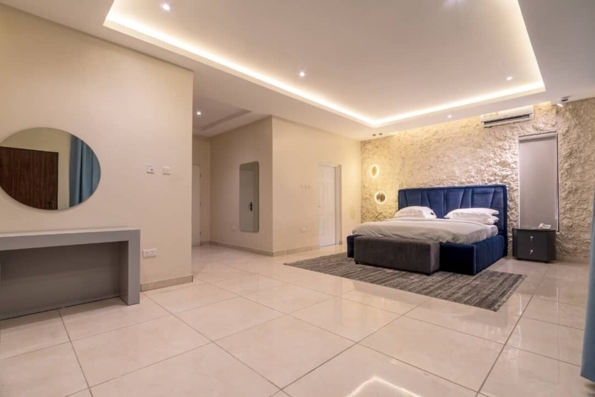 A modern bedroom with a large bed, a bedside table, and a built-in bench.