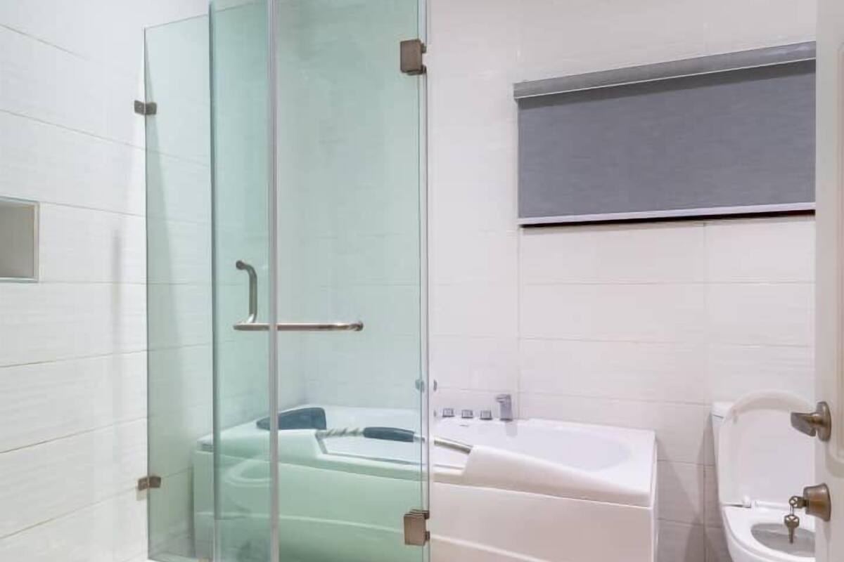 A modern bathroom with a glass-enclosed shower, a bathtub, and a toilet.