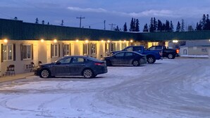 Un motel con varias habitaciones, un estacionamiento techado y suelo cubierto de nieve.