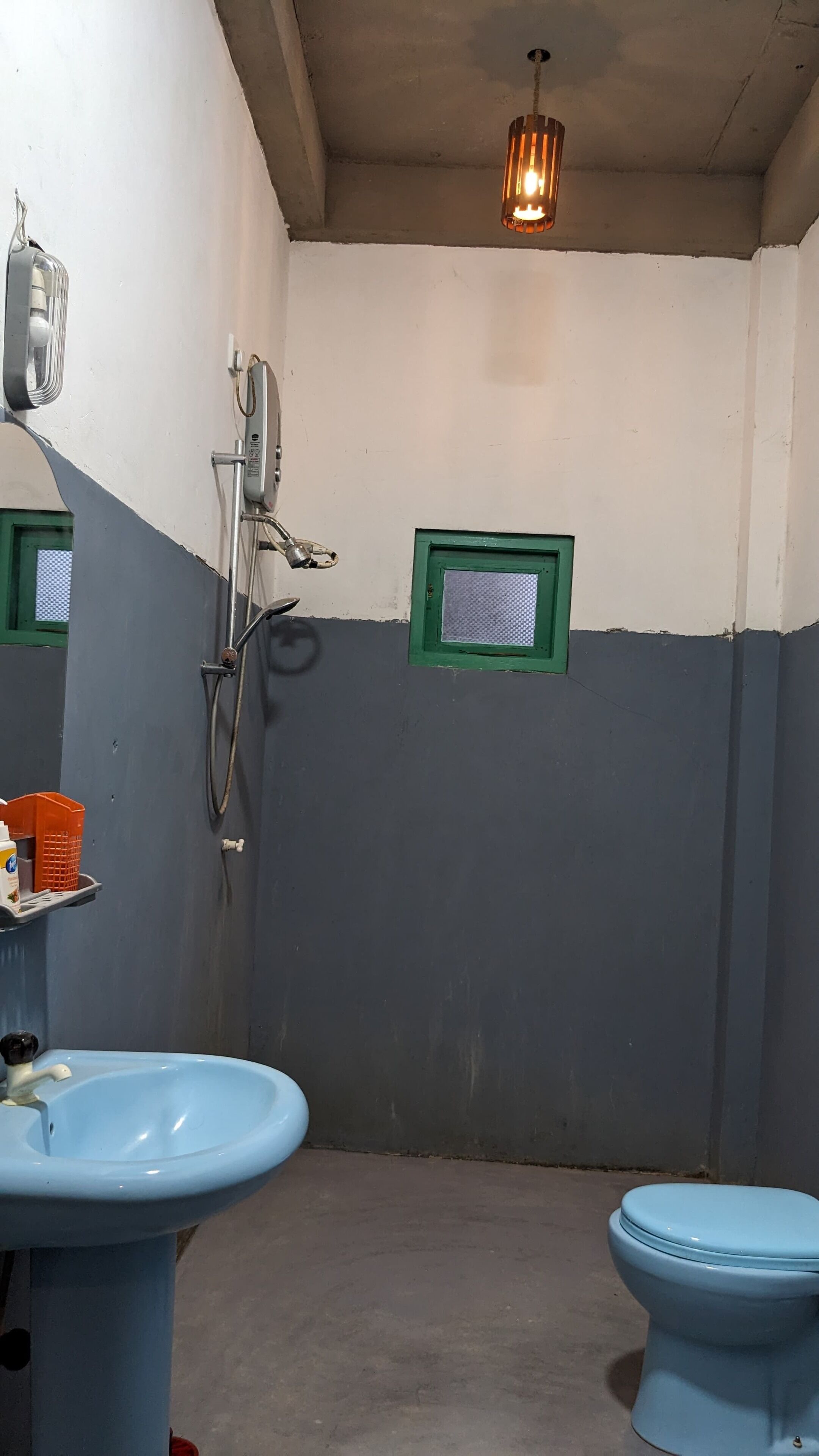 Een badkamer met een wastafel, toilet, douche en een klein raam.