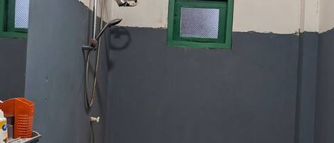 Een badkamer met een wastafel, toilet, douche en een klein raam.