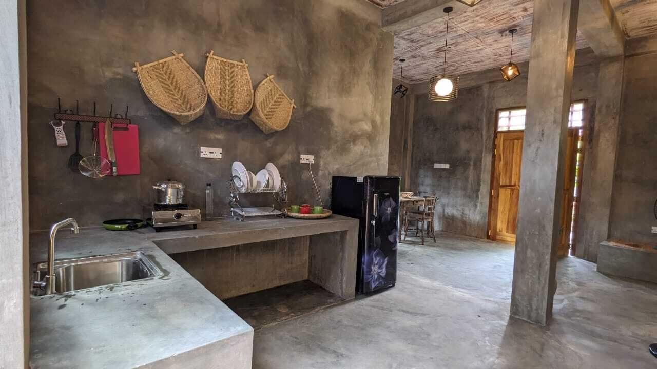 Een keuken met een beton aanrechtblad, hangende keukengerei en een koelkast.