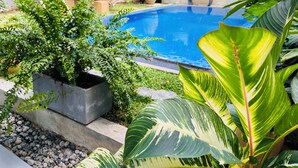 A swimming pool surrounded by lush greenery and potted plants. - Soul Villas (Tangalle)