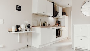 A modern kitchen with white cabinetry, a coffee machine, and a small countertop. - Wohnungtraveller Geislautern (Völklingen)